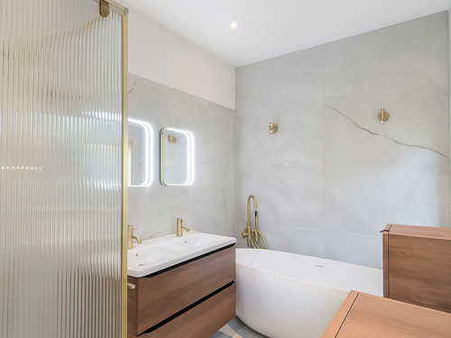 Modern bathroom with fluted glass shower screen, brushed brass taps and freestanding bath